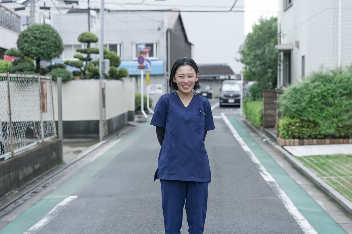 事務所前の道に立つ、笑顔の職員